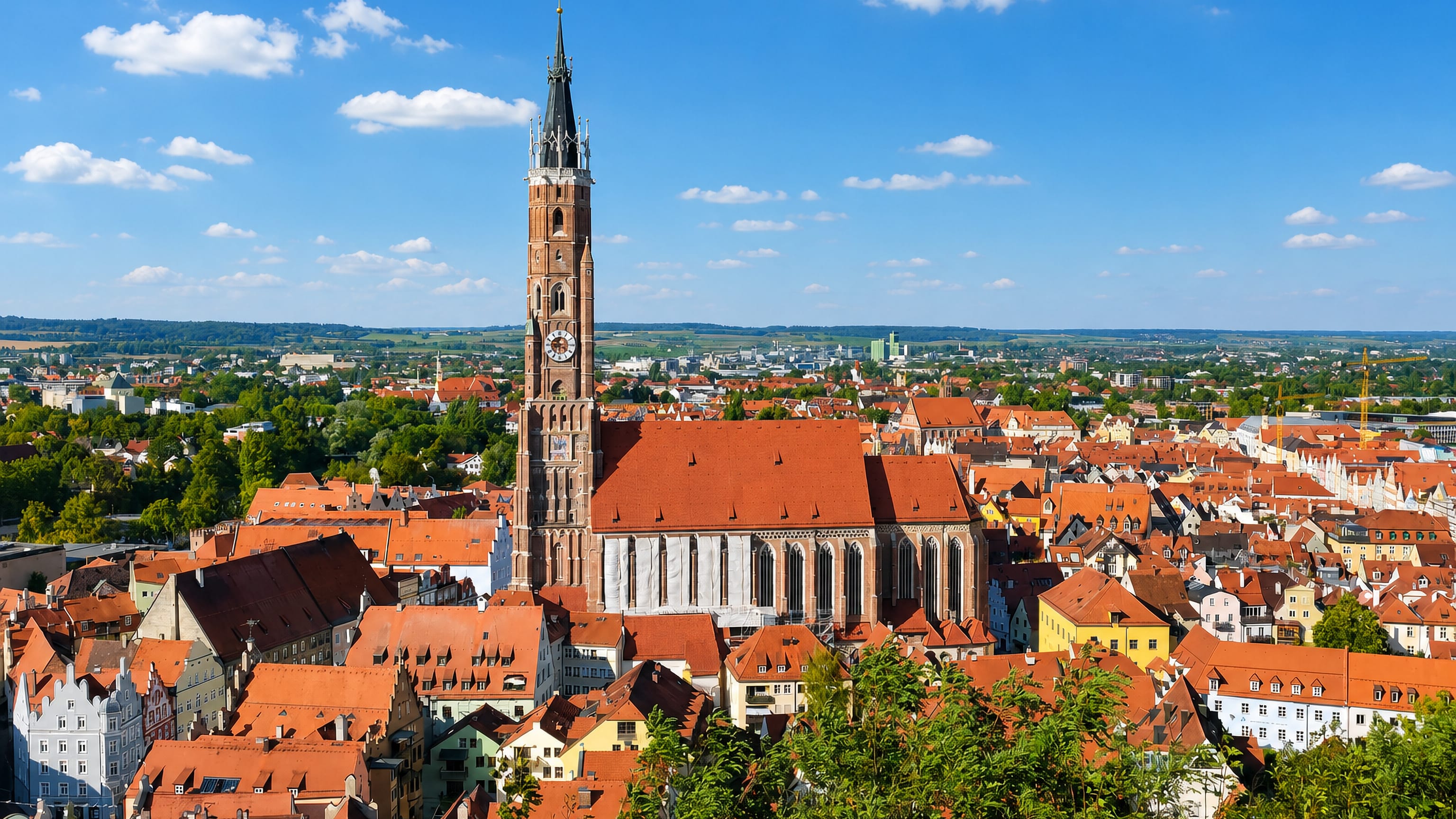 Landshut's old town in Bavaria beneath the tall brick spire of St Martin's Church and rows of red-tiled roofs.