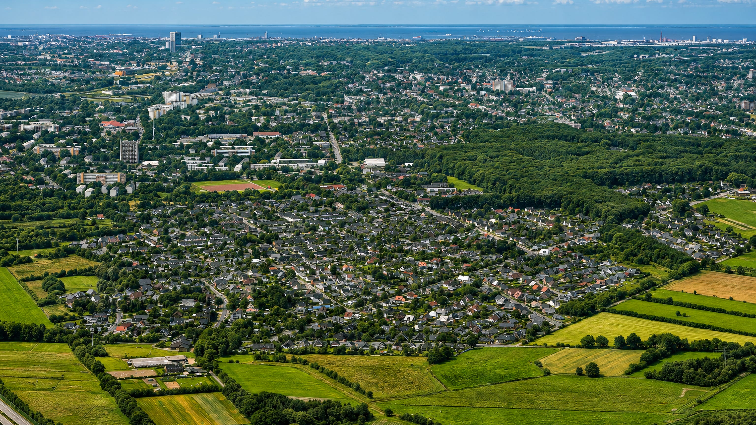 Aerial view over the housing estates and fields of Leherheide with Bremerhaven and the North Sea beyond.
