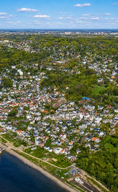 Aerial of the Elbe beach and leafy villa district of Altona, Hamburg, with a small red-and-white lighthouse on the shore