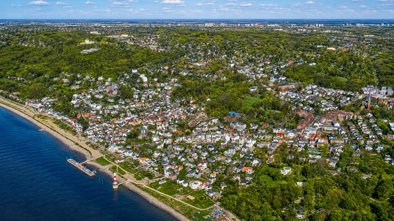 Aerial of the Elbe beach and leafy villa district of Altona, Hamburg, with a small red-and-white lighthouse on the shore