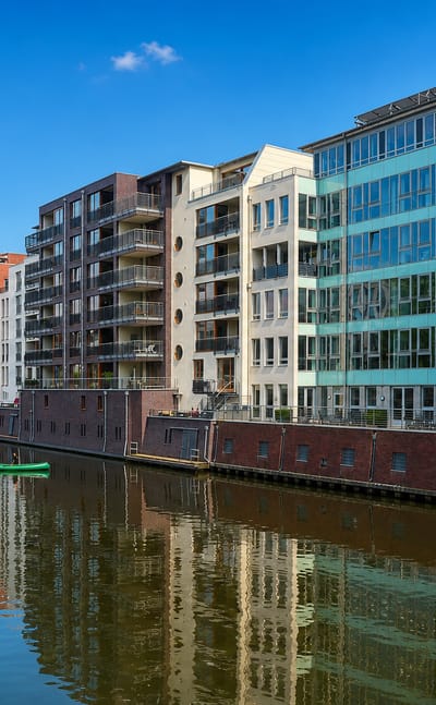 Modern waterside apartment buildings reflected in a canal under blue sky in Barmbek-Sud, Hamburg