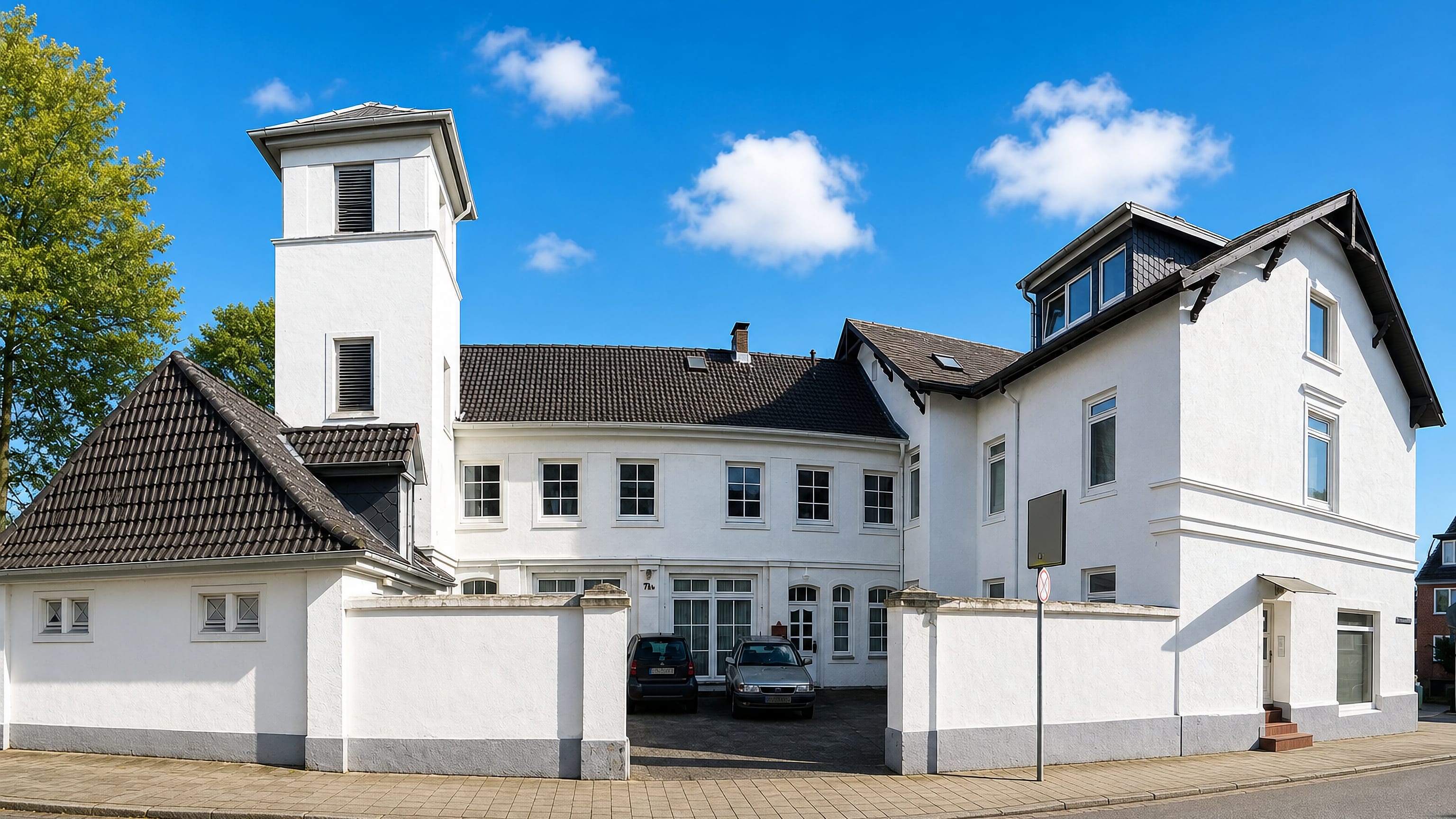 White gabled corner building with a small tower on a quiet residential street in Billstedt, Hamburg.