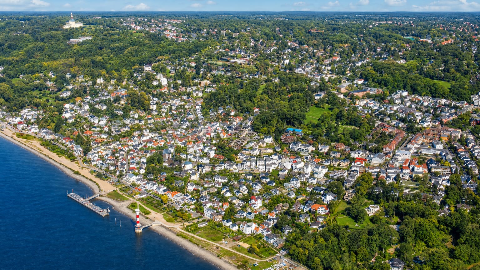 Aerial of hillside villas descending to the Elbe riverside beach and lighthouse in Blankenese, Hamburg