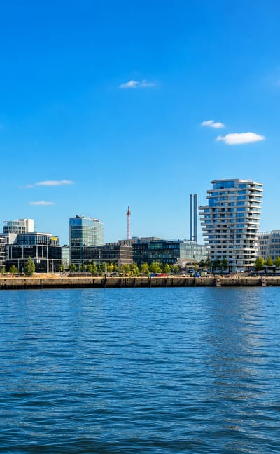 Hamburg's HafenCity waterfront on the Elbe, with the wave-topped Marco Polo Tower and modern quayside buildings.