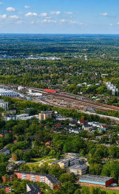 Aerial view of green suburban Eidelstedt in Hamburg with rail lines, apartment blocks and low-rise housing among trees