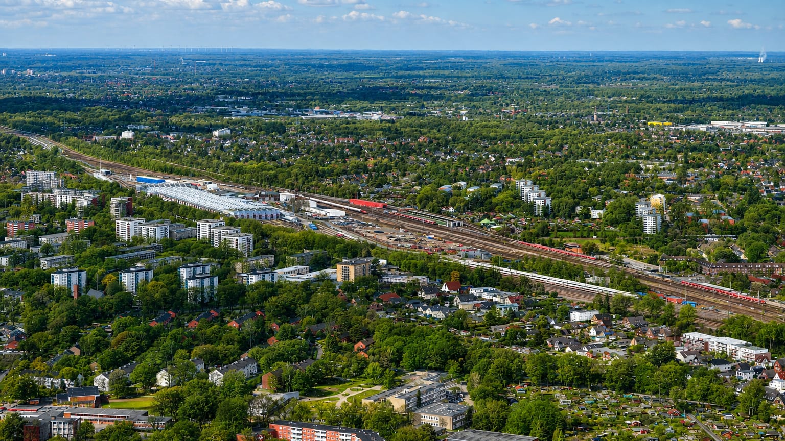 Aerial view of green suburban Eidelstedt in Hamburg with rail lines, apartment blocks and low-rise housing among trees