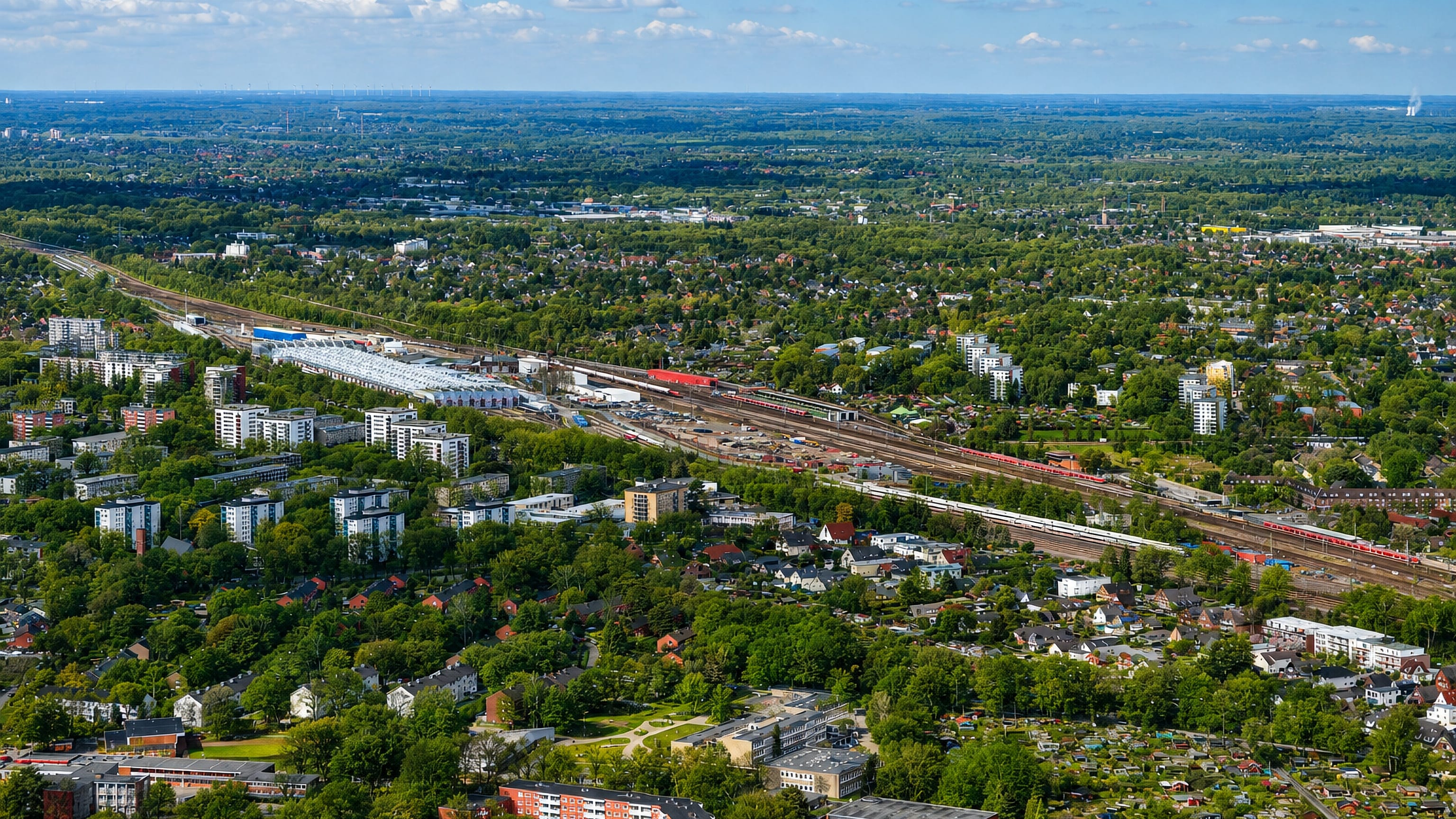 Aerial view of green suburban Eidelstedt in Hamburg with rail lines, apartment blocks and low-rise housing among trees