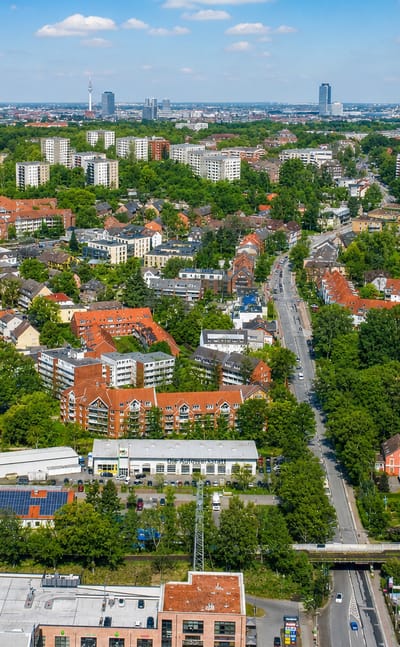 Aerial over the dense Eimsbüttel district of Hamburg with the Heinrich-Hertz TV tower and city skyline on the horizon