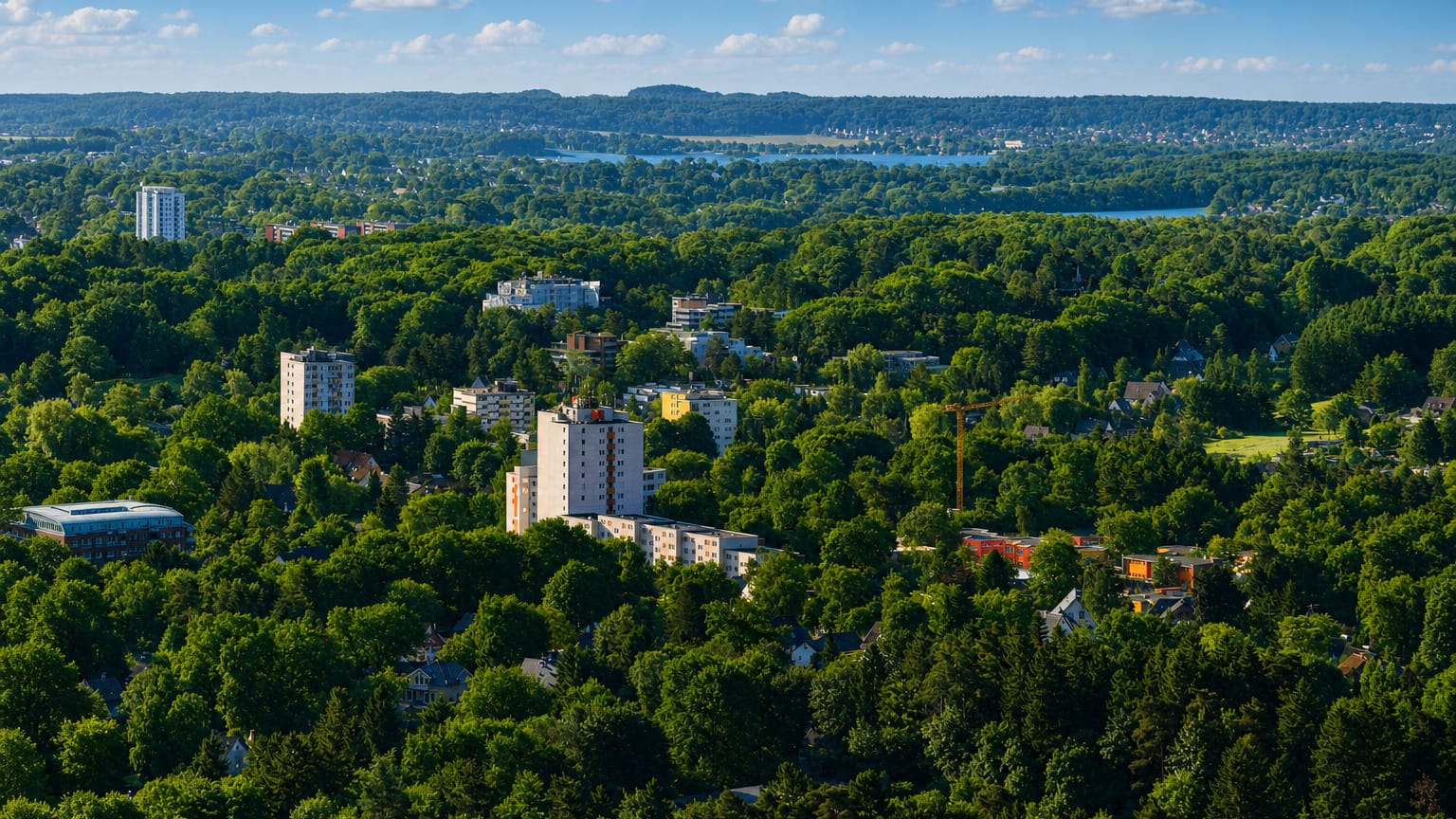 Aerial view over Eissendorf, a green Hamburg-Harburg district of low houses and white apartment towers among dense woodland with hills and water beyond