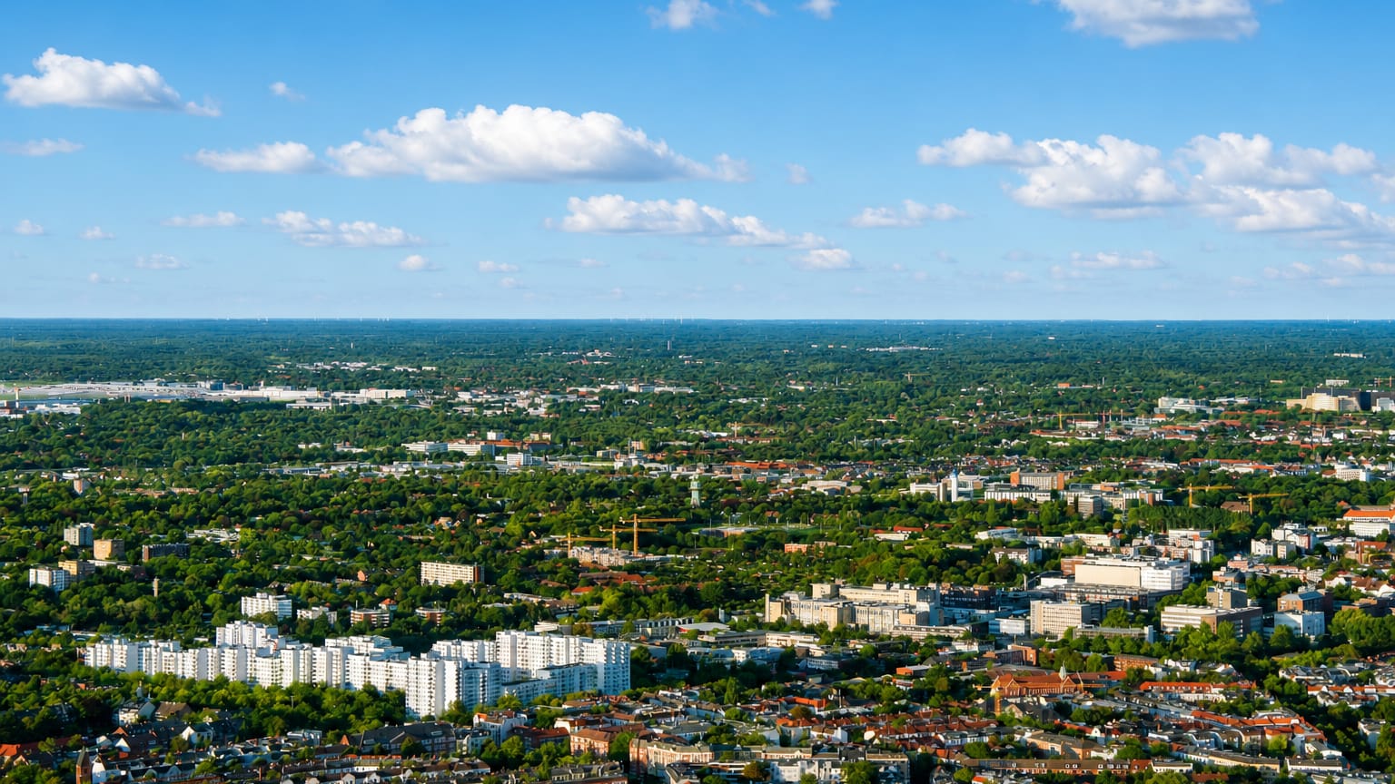 Aerial cityscape of white apartment blocks and low red-roofed housing amid greenery in Eppendorf, Hamburg.