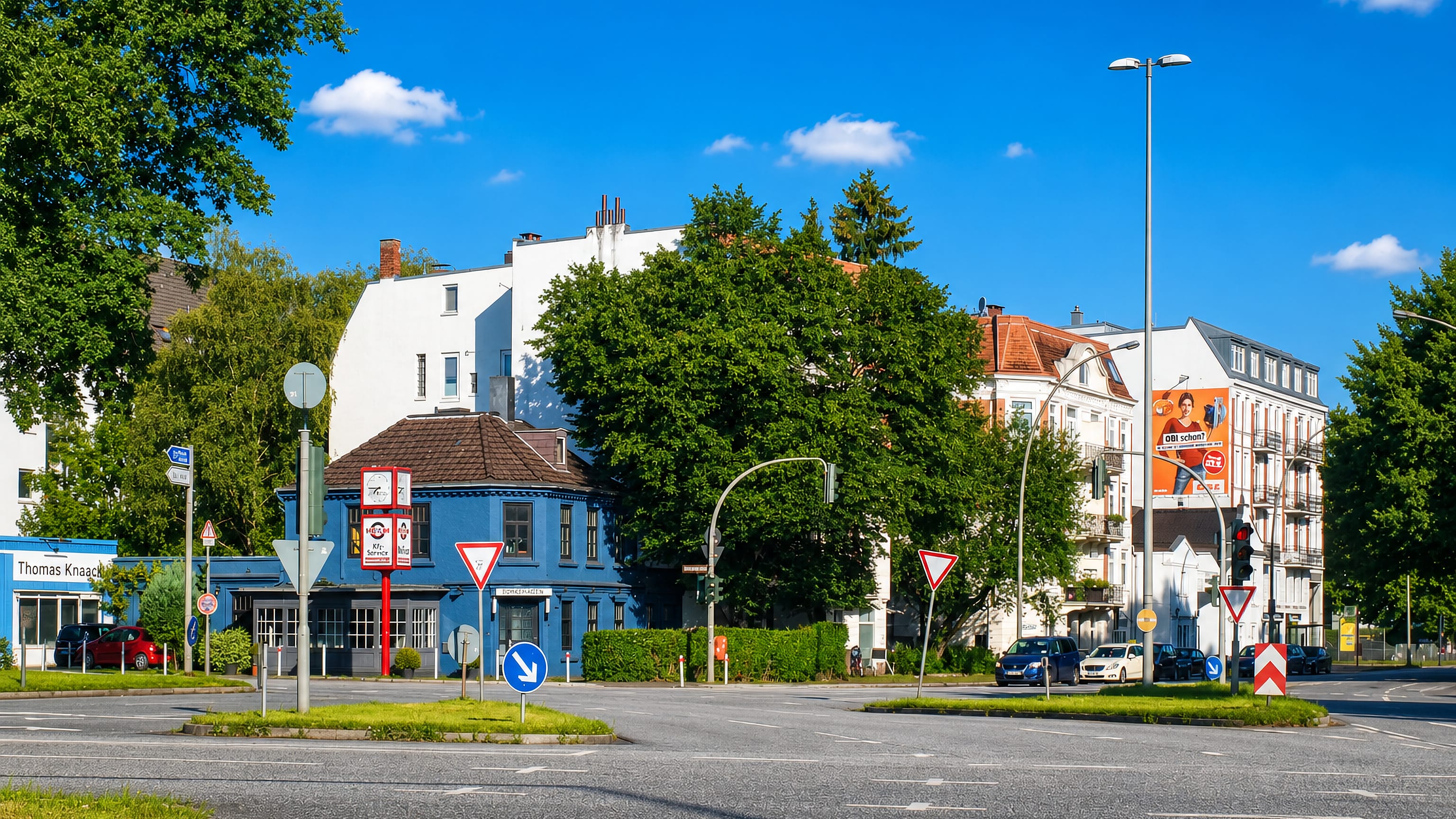 Street corner in Groß Borstel, Hamburg, with a blue Altbau building and a broad road junction under a clear sky