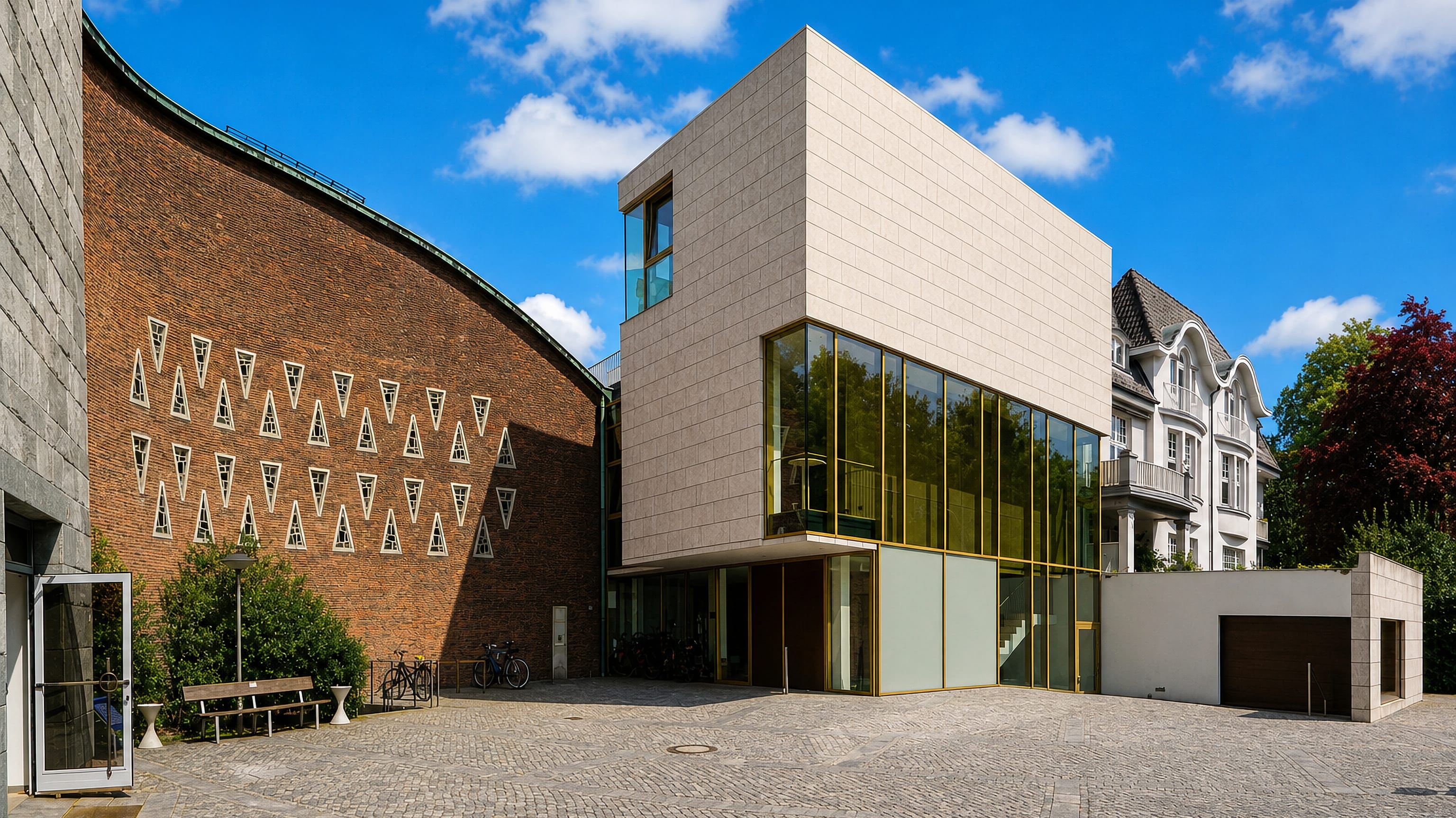 A cobbled courtyard between a patterned brick facade and a modern stone gallery in Hamburg's Harvestehude.