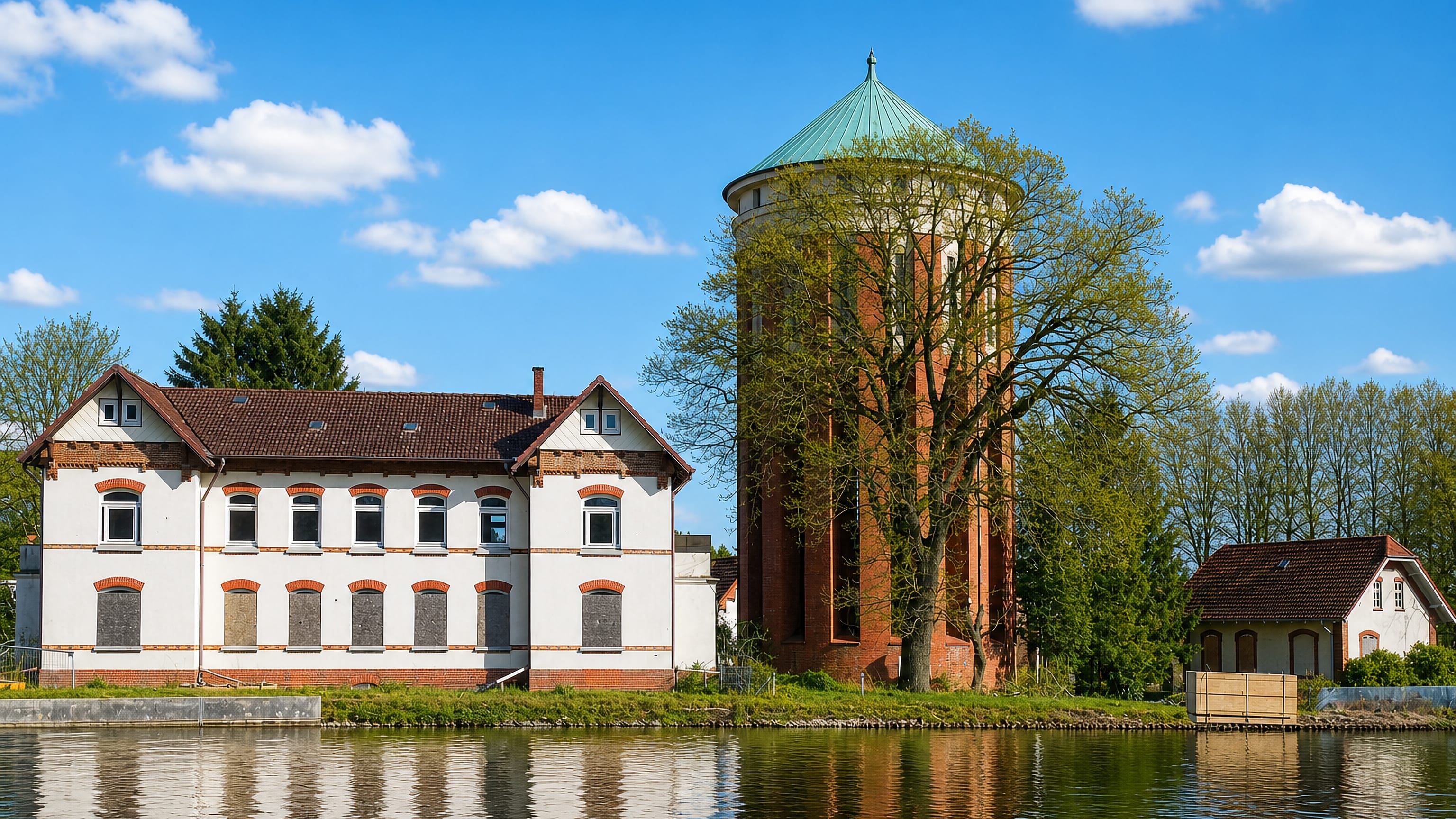 The brick water tower and pond-side buildings of Langenhorn in northern Hamburg under a spring sky.