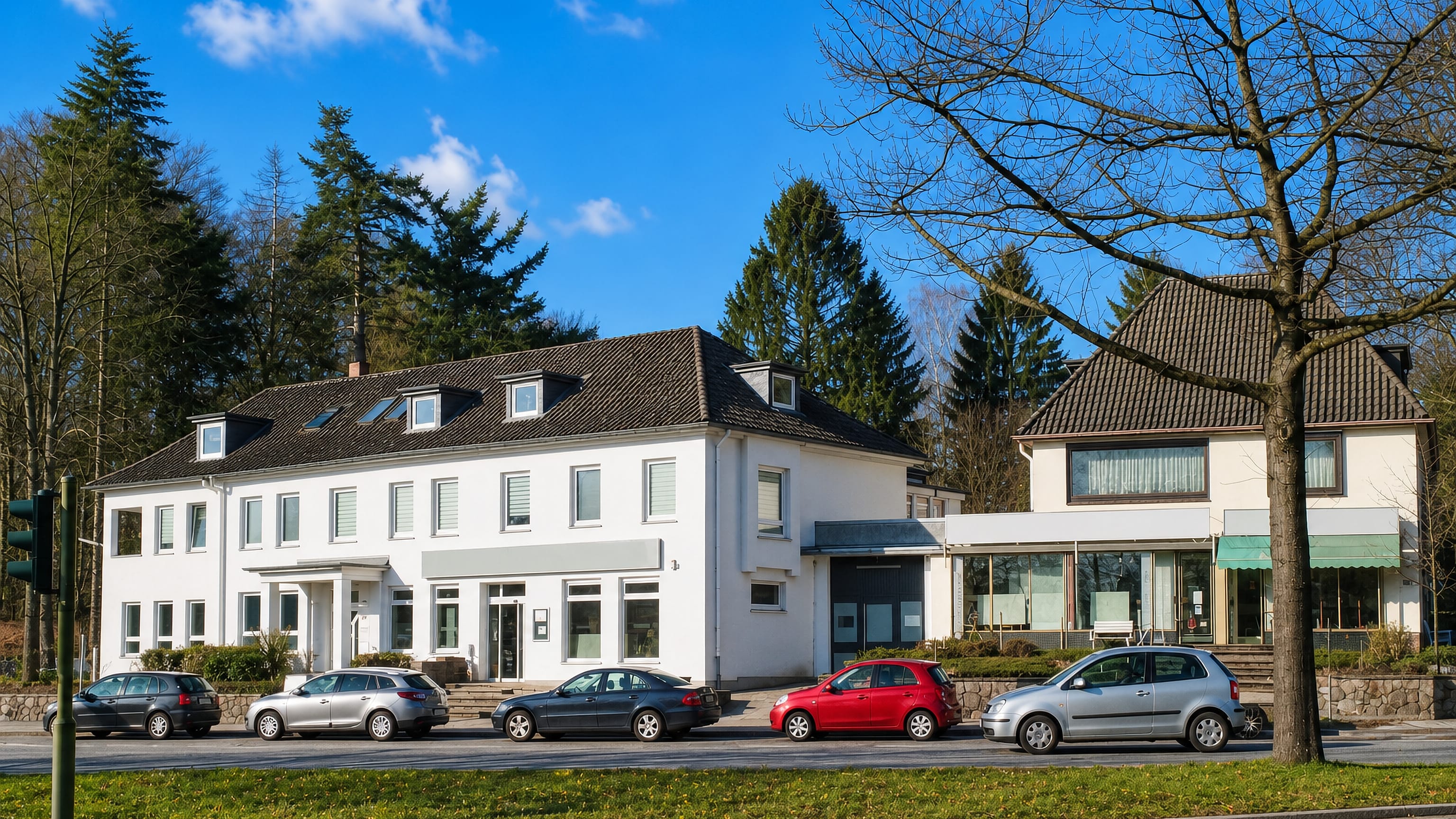 White roadside apartment and shop building behind parked cars on a main road in Poppenbüttel, Hamburg.