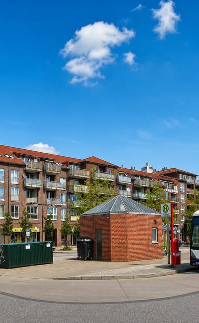 Street-level square with brick apartment blocks, a bus stop pavilion and an articulated transit bus in Schnelsen, Hamburg