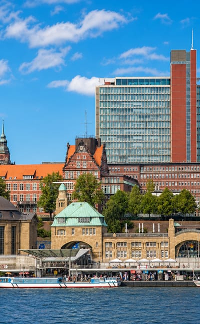 The arcaded copper-domed St. Pauli Landungsbrücken piers on the Elbe waterfront with modern towers behind in Hamburg.