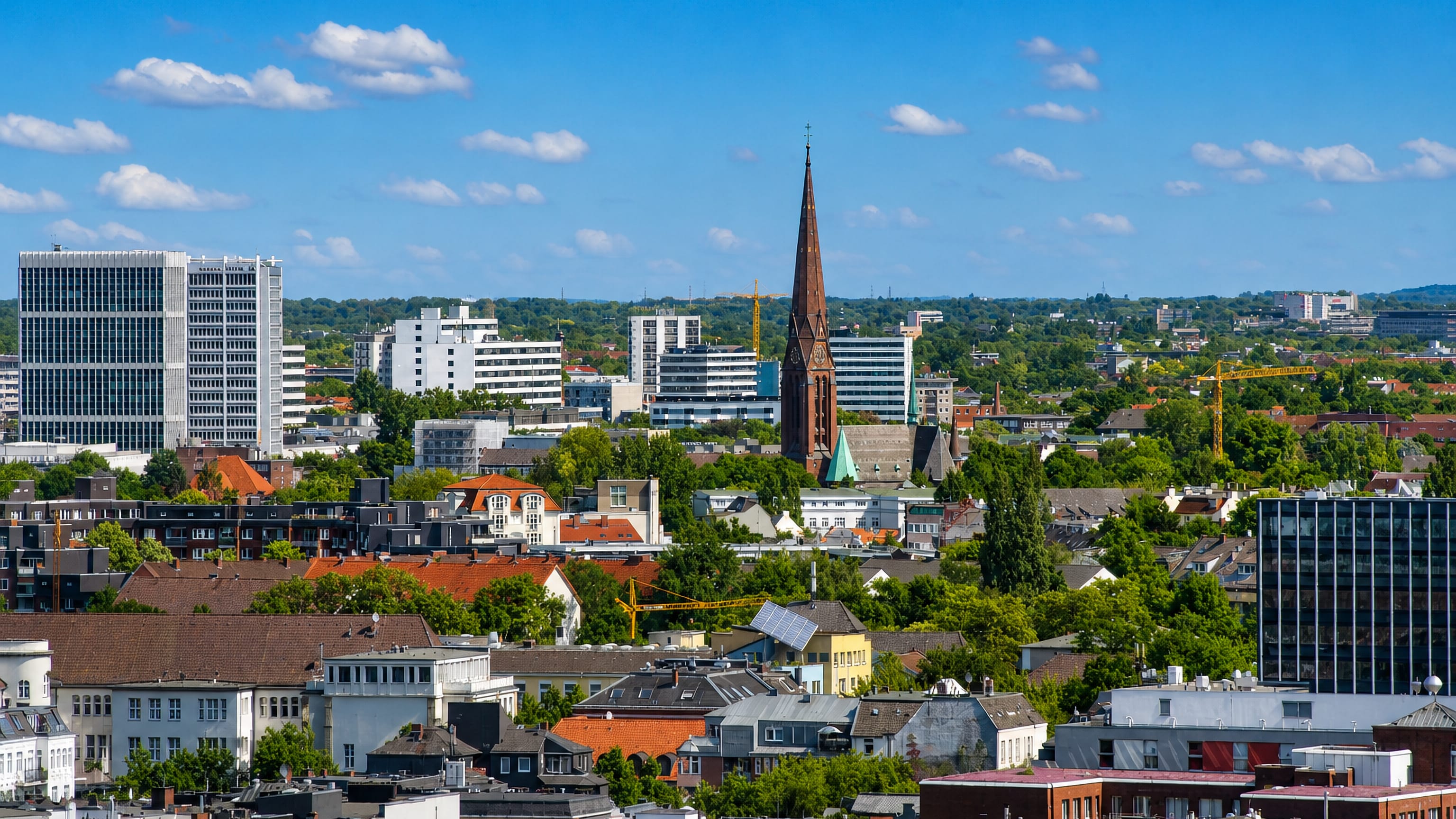 Rooftops of Hamburg's Uhlenhorst district under a blue sky, with a brick church spire and office blocks behind