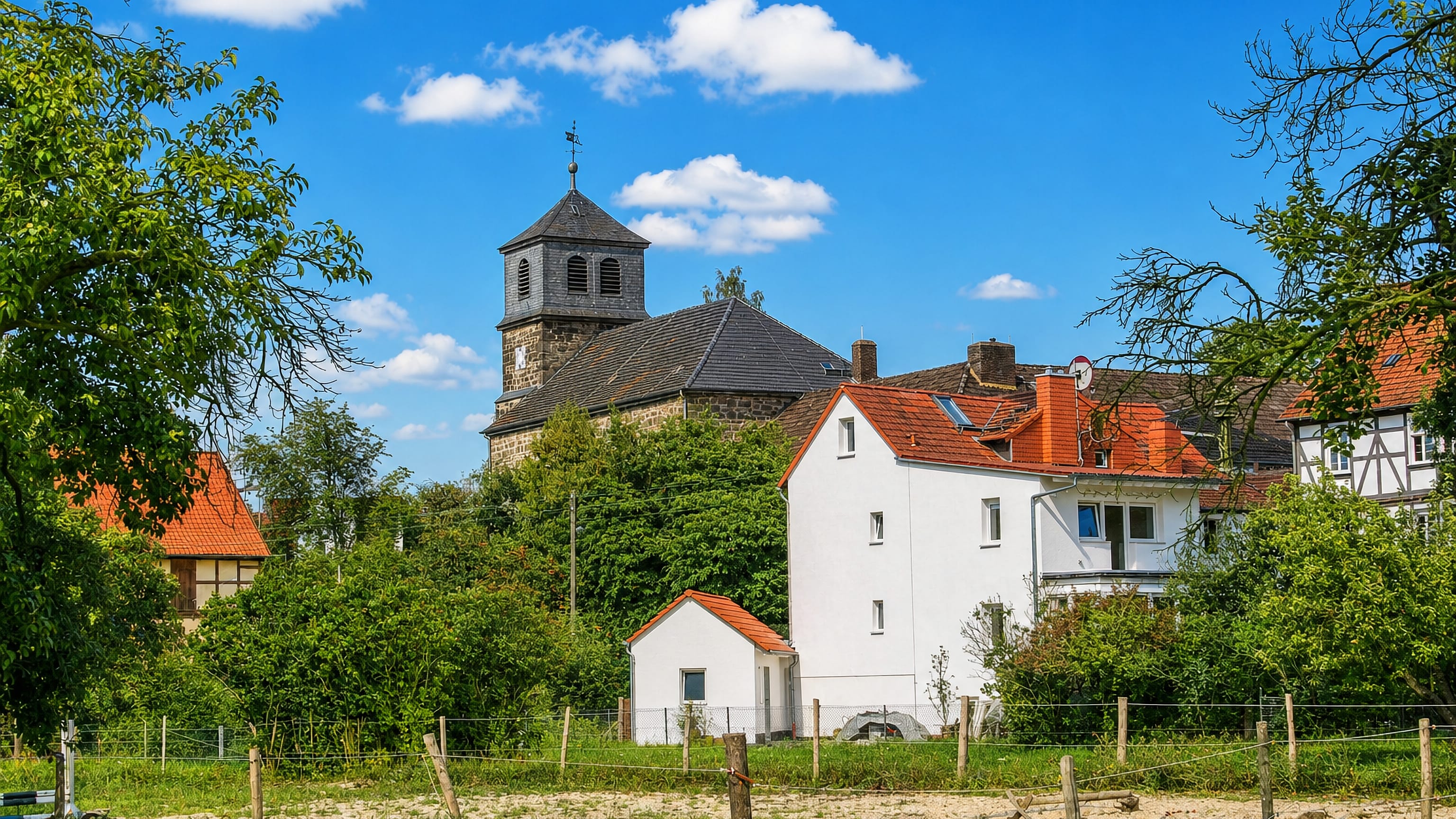 Village church tower and half-timbered houses of Oberzwehren above a meadow, Kassel.