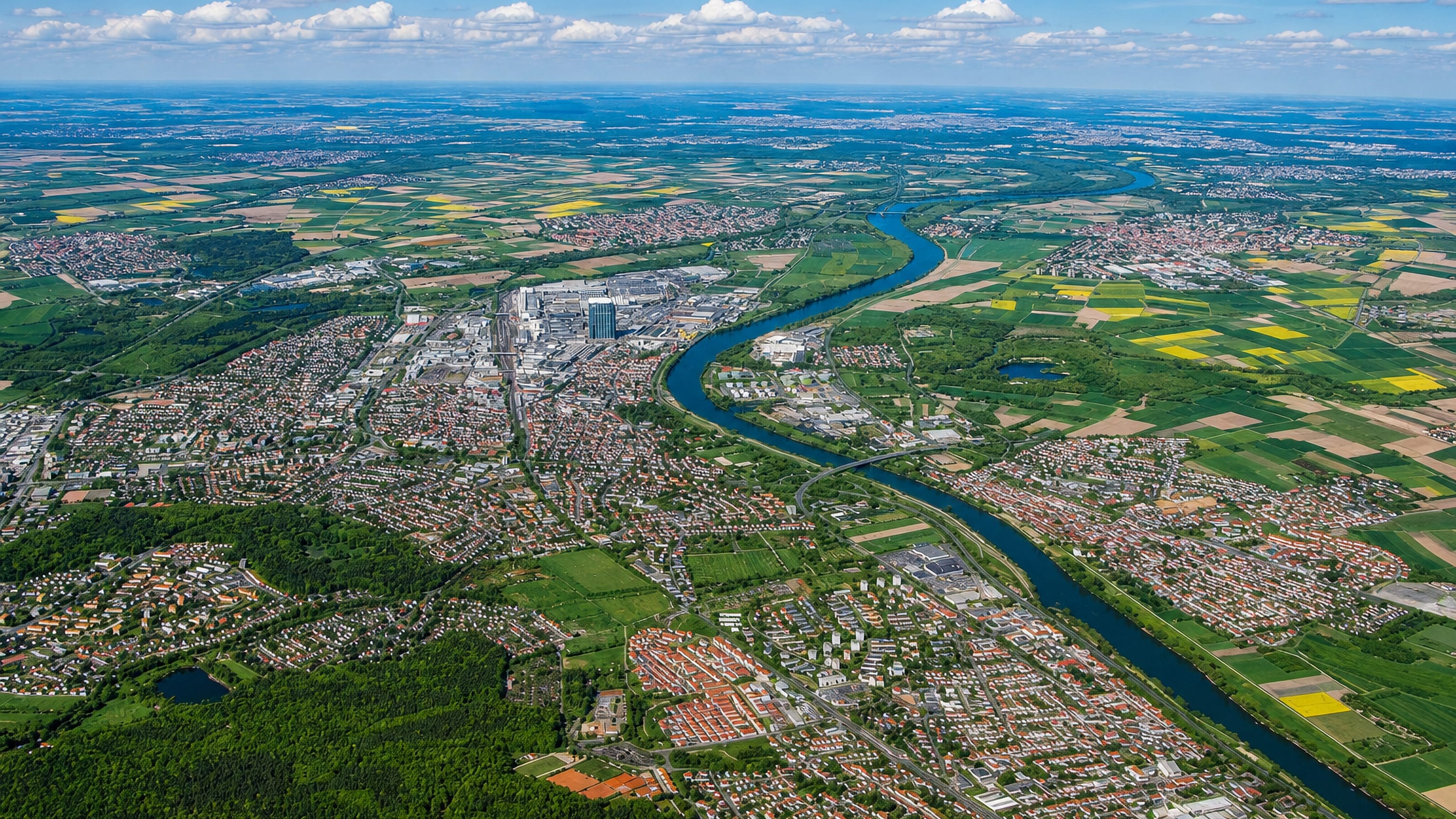 High aerial of Russelsheim am Main along the River Main beside its large factory complex and farmland.