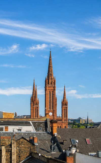 Wiesbaden rooftops beneath the red-brick neo-Gothic Marktkirche and its towering central spire under a blue sky