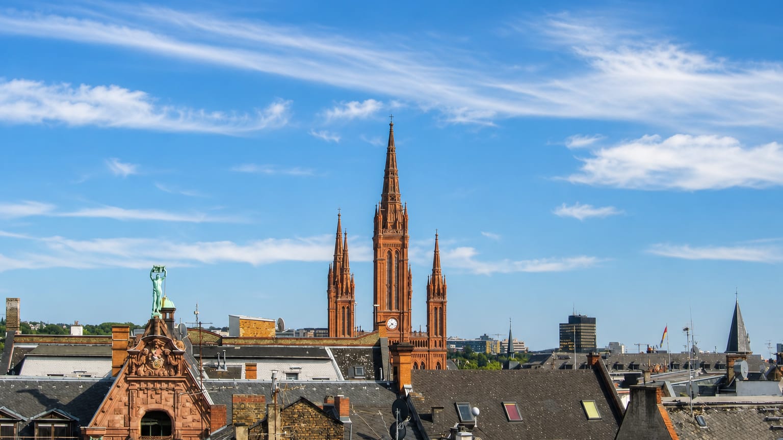 Wiesbaden rooftops beneath the red-brick neo-Gothic Marktkirche and its towering central spire under a blue sky