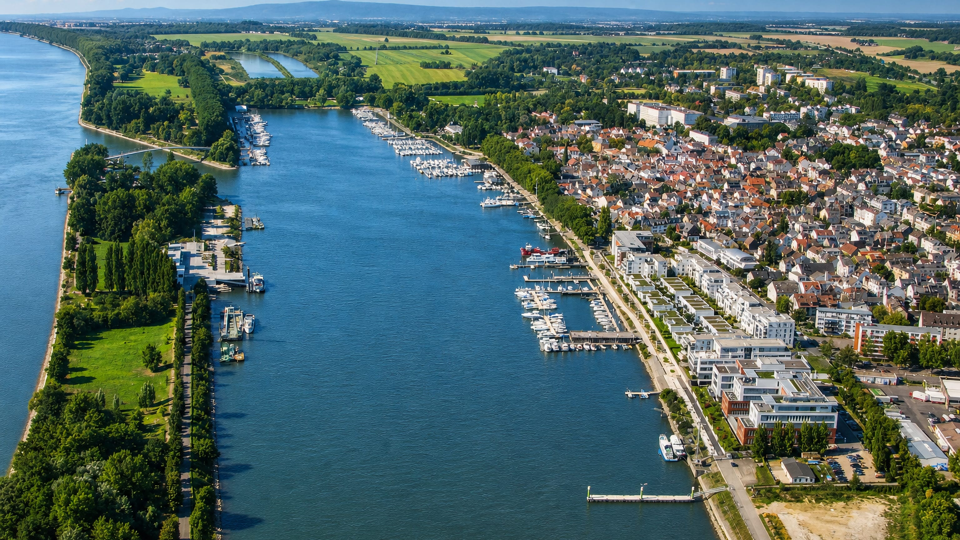 Aerial view of Schierstein, Wiesbaden, its Rhine marina packed with yachts opposite a wooded island.