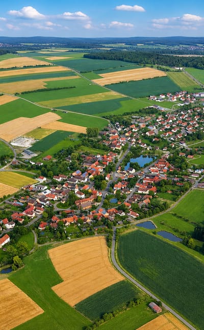 Aerial of a small village ringed by patchwork farm fields and forest near Buch, Berlin