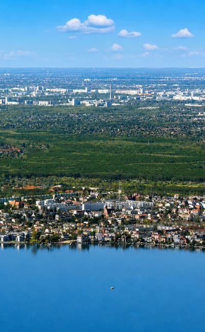 Aerial view of Friedrichshagen on the shore of Berlin's Müggelsee, ringed by forest with the city beyond.