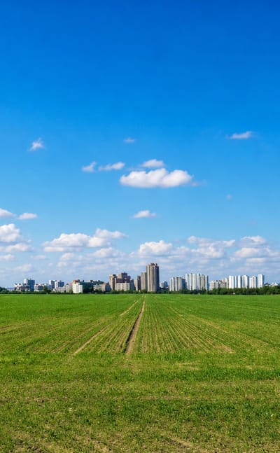 Distant high-rise skyline of the Gropiusstadt estate seen across an open green field in Berlin