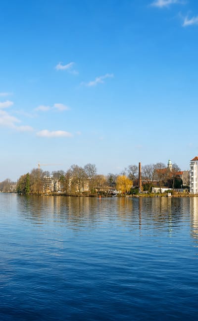 Waterfront view of Berlin's Koepenick district with historic buildings and church towers reflected in the river