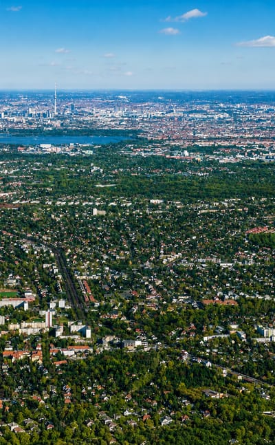 Aerial view over the leafy low-rise suburb of Lichtenrade, Berlin, with a lake and the distant city skyline.