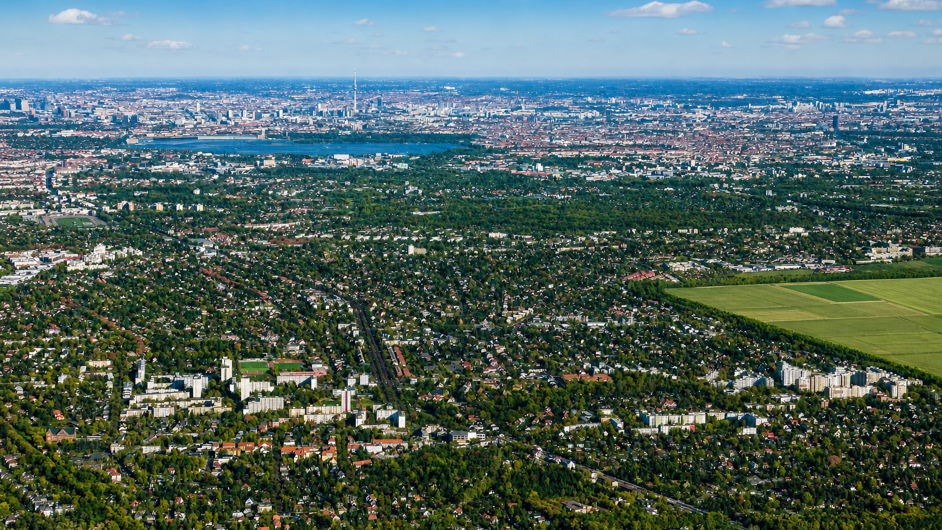 Aerial view over the leafy low-rise suburb of Lichtenrade, Berlin, with a lake and the distant city skyline.
