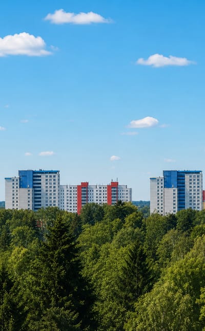 Cluster of high-rise apartment towers rising above a dense tree line in Lichterfelde, Berlin, under a clear sky
