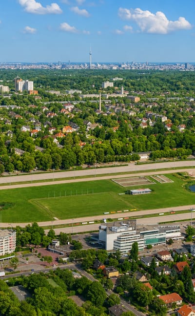 Aerial view of Berlin's Mariendorf harness-racing track with the district's housing and the distant city skyline