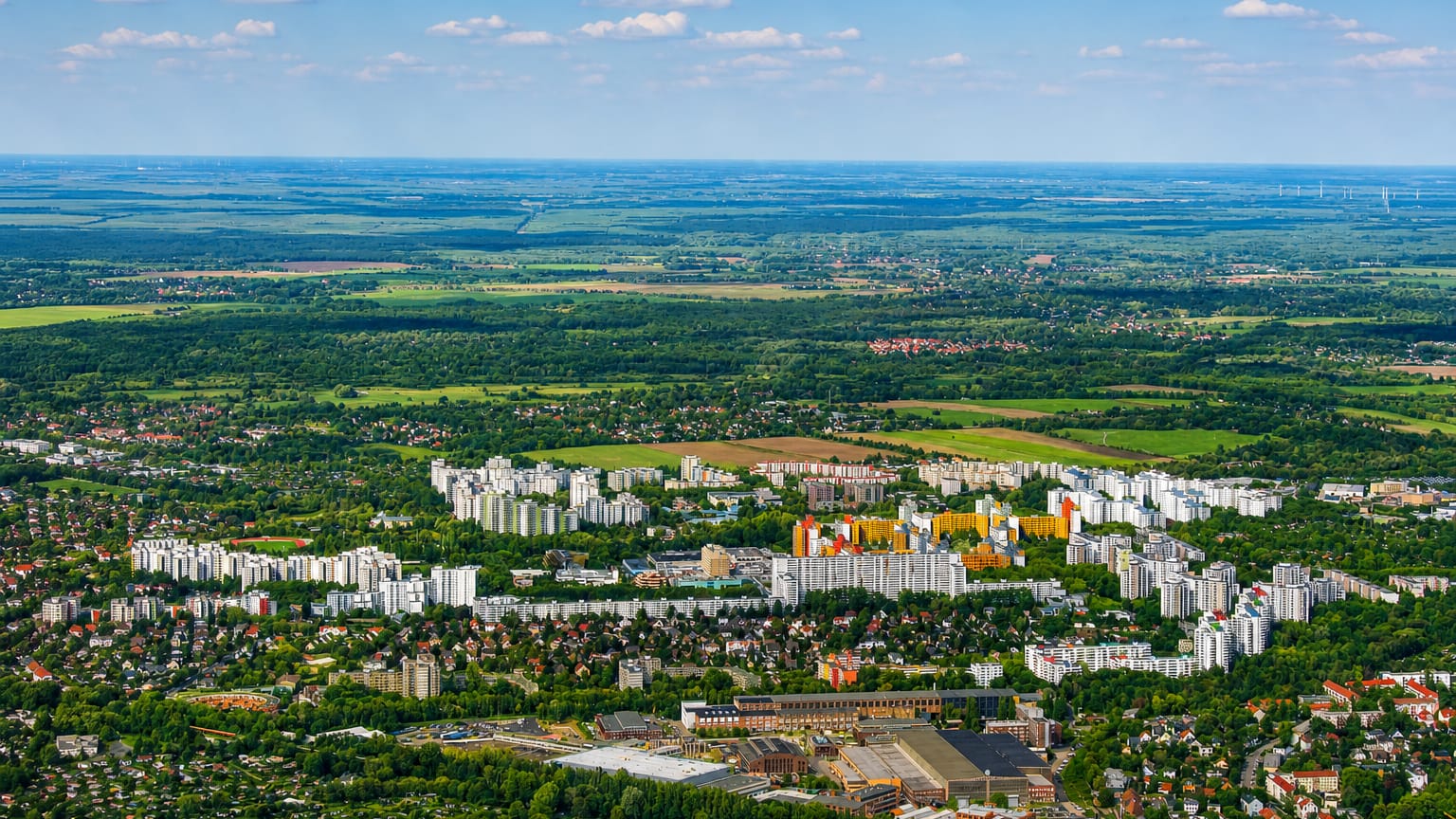 High-altitude aerial of Berlin's Maerkisches Viertel showing its colourful high-rise housing estate amid surrounding greenery