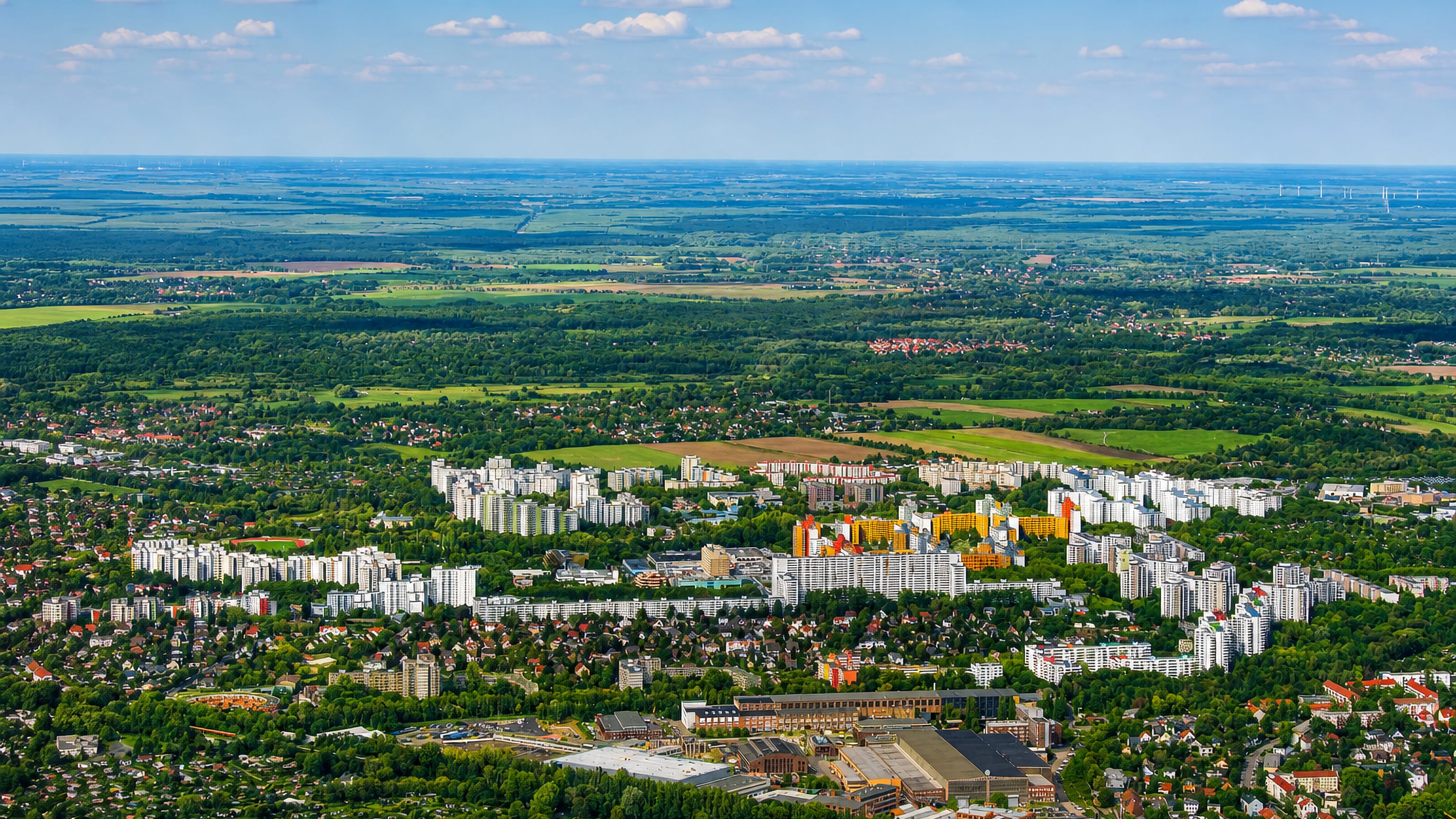 High-altitude aerial of Berlin's Maerkisches Viertel showing its colourful high-rise housing estate amid surrounding greenery