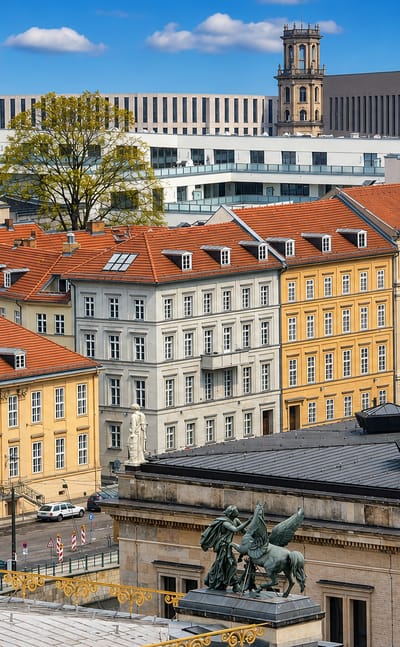 Rooftop view over ochre facades, red-tiled roofs and a bronze quadriga in central Berlin's Mitte district.