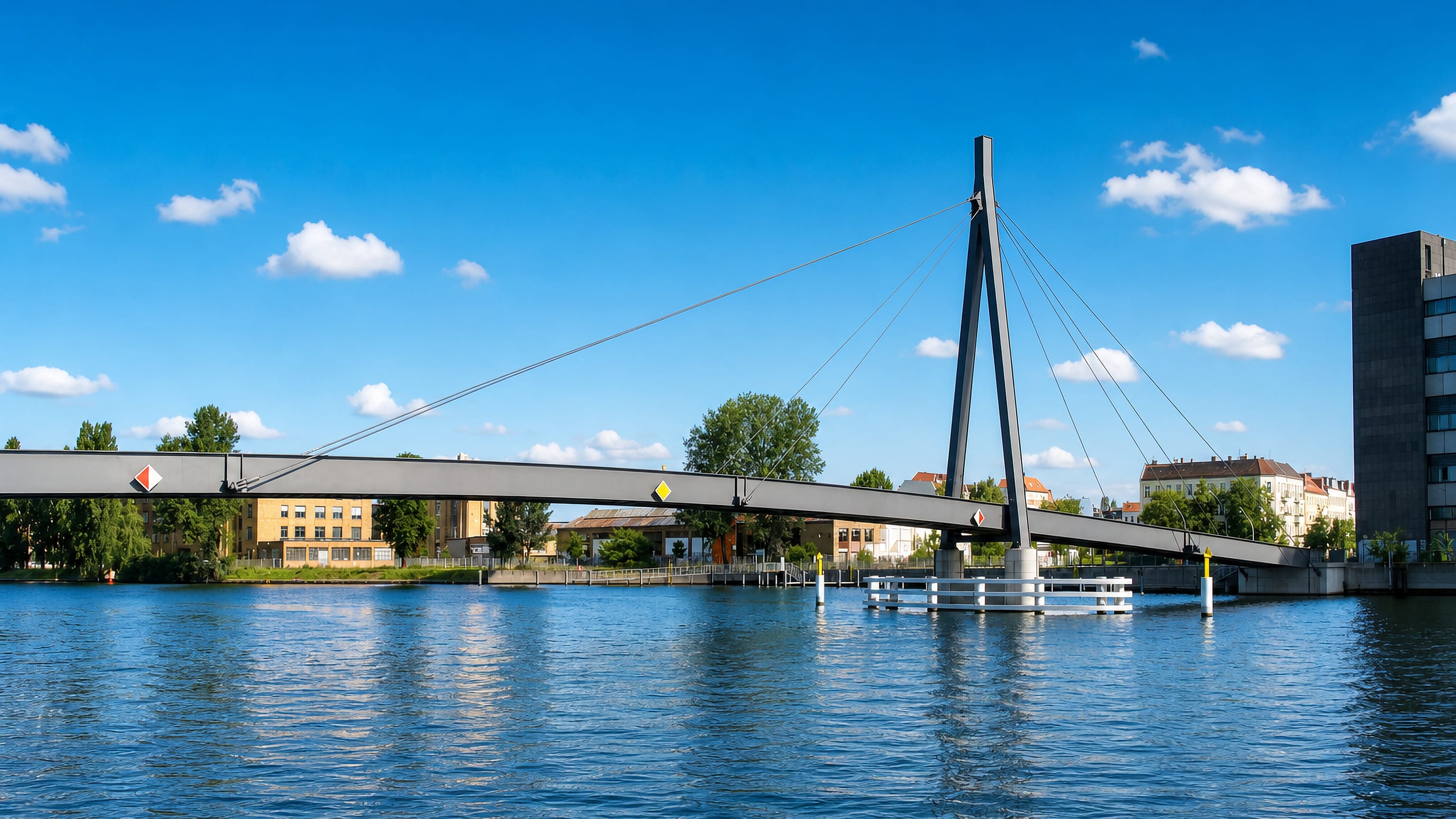 The cable-stayed Kaisersteg footbridge crossing the Spree to Oberschöneweide in Berlin, with riverside buildings behind.