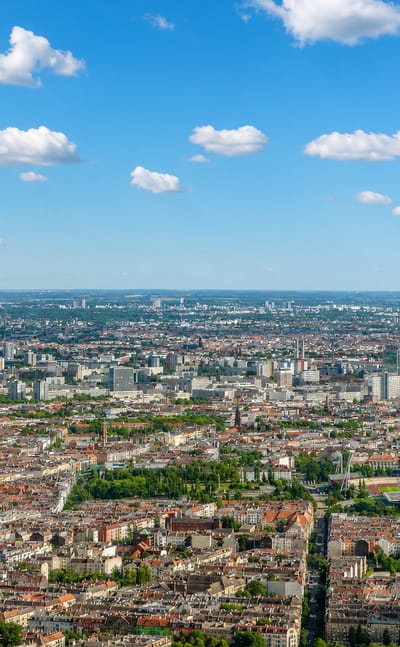 Wide aerial of Prenzlauer Berg's dense old tenement rooftops with the Berlin TV Tower rising on the skyline.