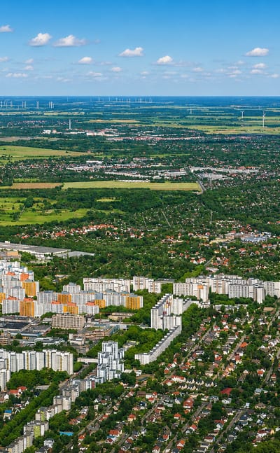 Wide aerial of Reinickendorf in Berlin showing housing estates and suburban streets fading to fields and wind turbines