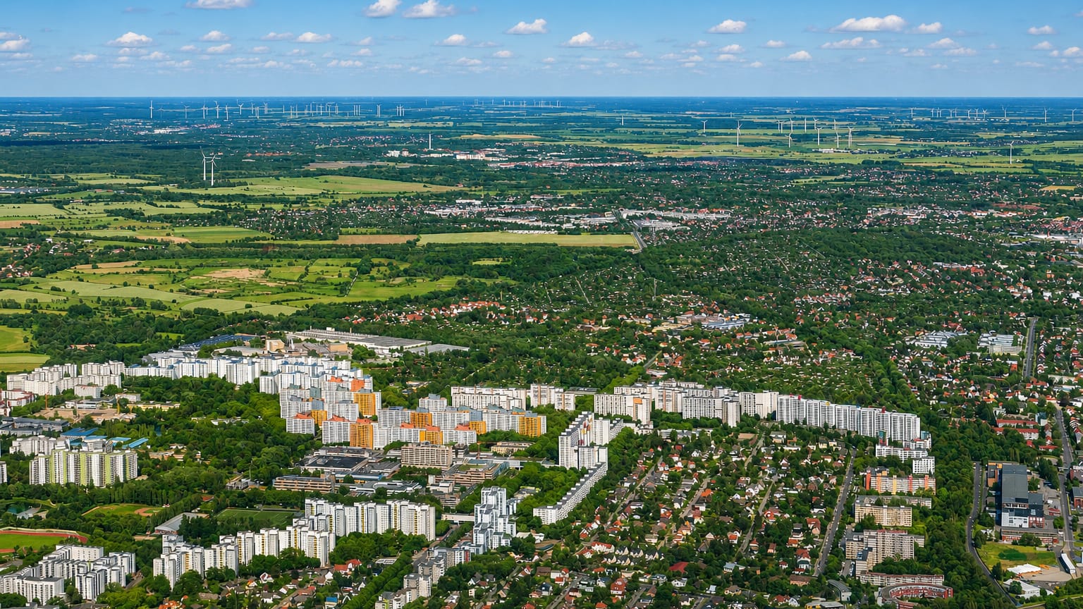 Wide aerial of Reinickendorf in Berlin showing housing estates and suburban streets fading to fields and wind turbines