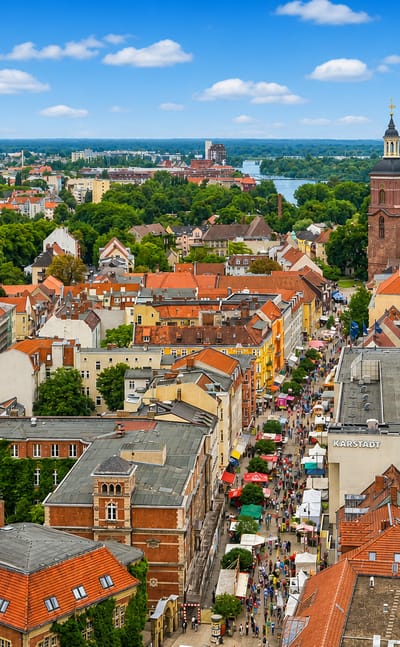 Aerial view of Spandau old town in Berlin with St. Nikolai church tower, red-roofed houses and the Havel river beyond.