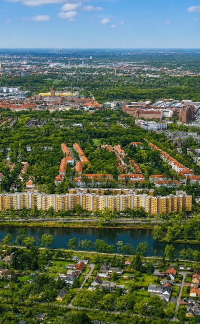 Aerial view of Tegel in Berlin, a waterside housing estate ringed by allotment gardens and greenery under a hazy skyline