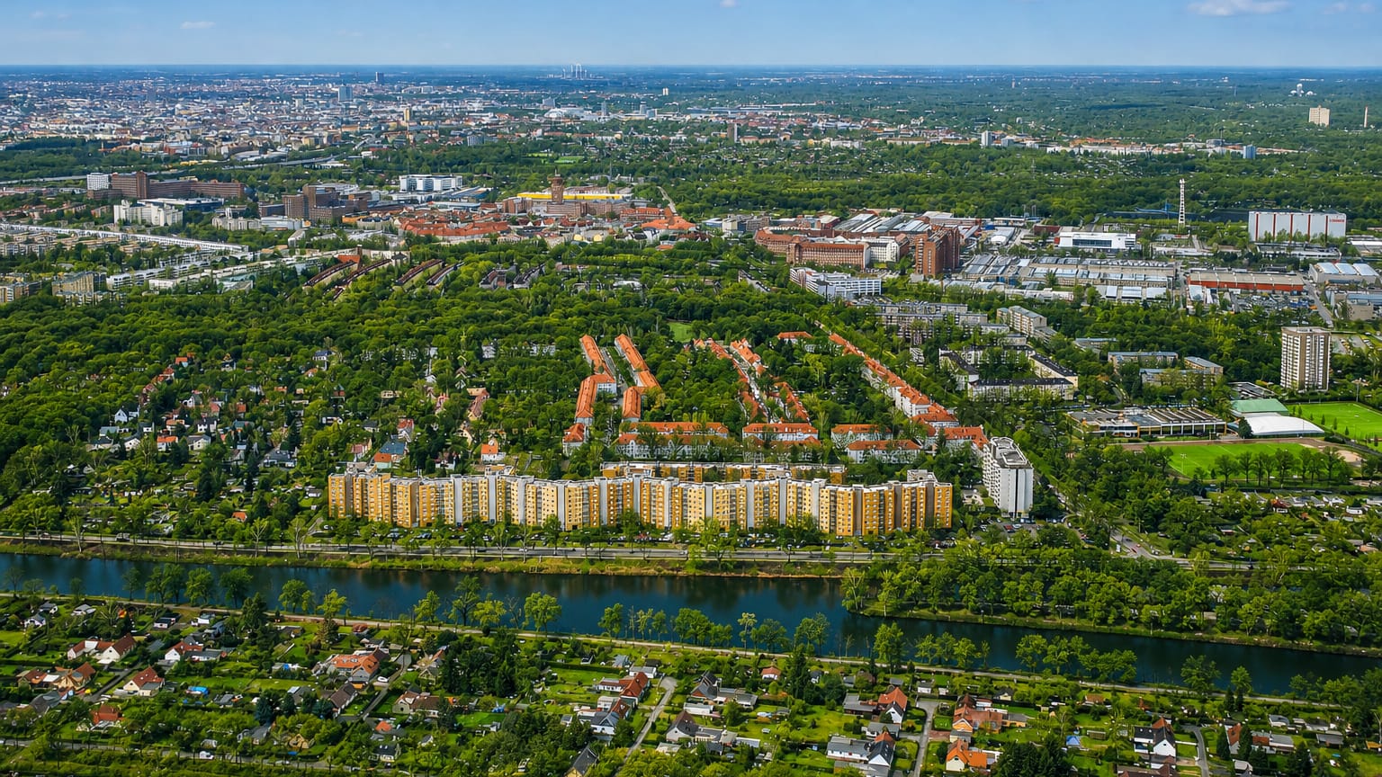 Aerial view of Tegel in Berlin, a waterside housing estate ringed by allotment gardens and greenery under a hazy skyline