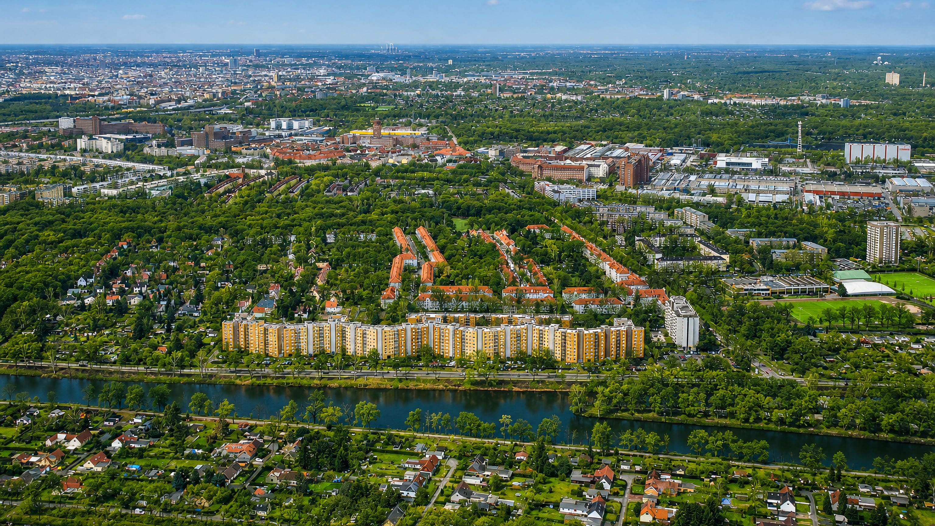 Aerial view of Tegel in Berlin, a waterside housing estate ringed by allotment gardens and greenery under a hazy skyline