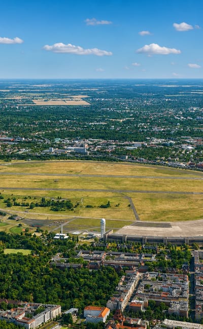 Aerial view of Tempelhofer Feld, the former Tempelhof airport, with its oval field and sweeping curved terminal in Berlin.