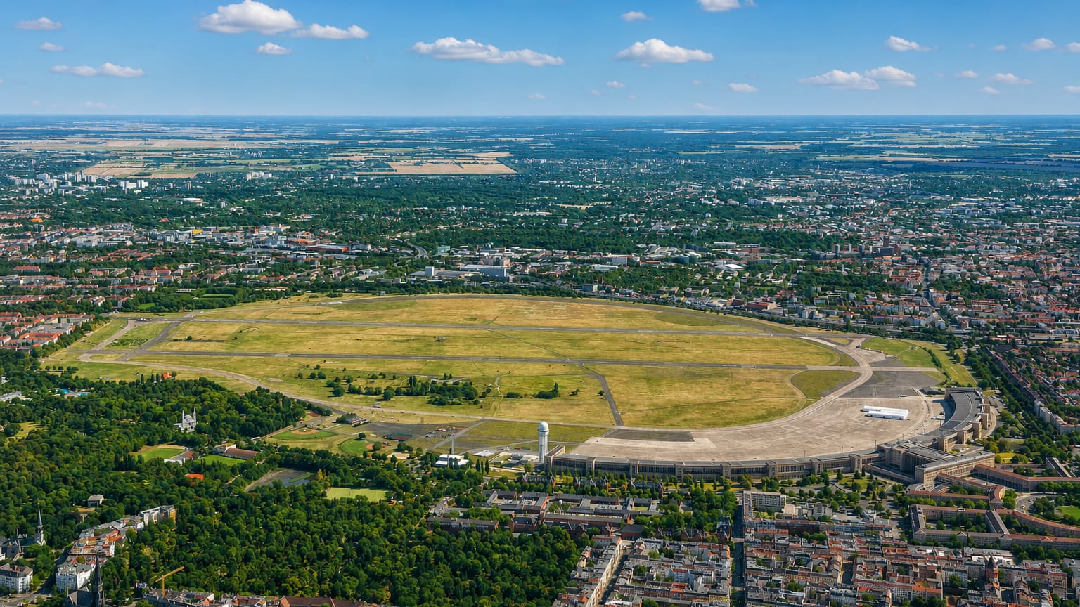 Aerial view of Tempelhofer Feld, the former Tempelhof airport, with its oval field and sweeping curved terminal in Berlin.