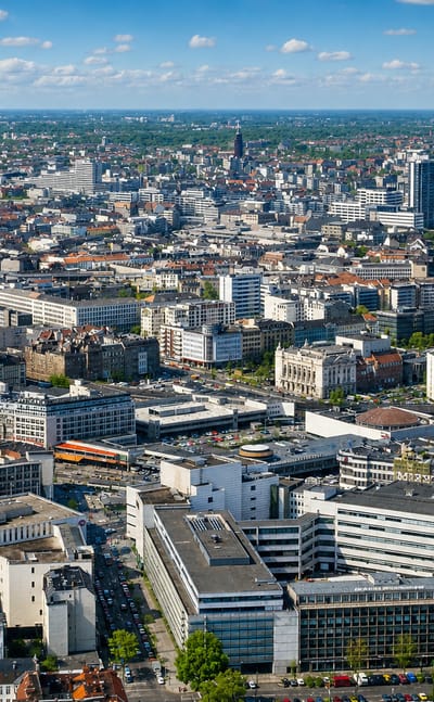 Aerial over the dense rooftops and streets of Wilmersdorf, a central district of Berlin, under a clear sky.