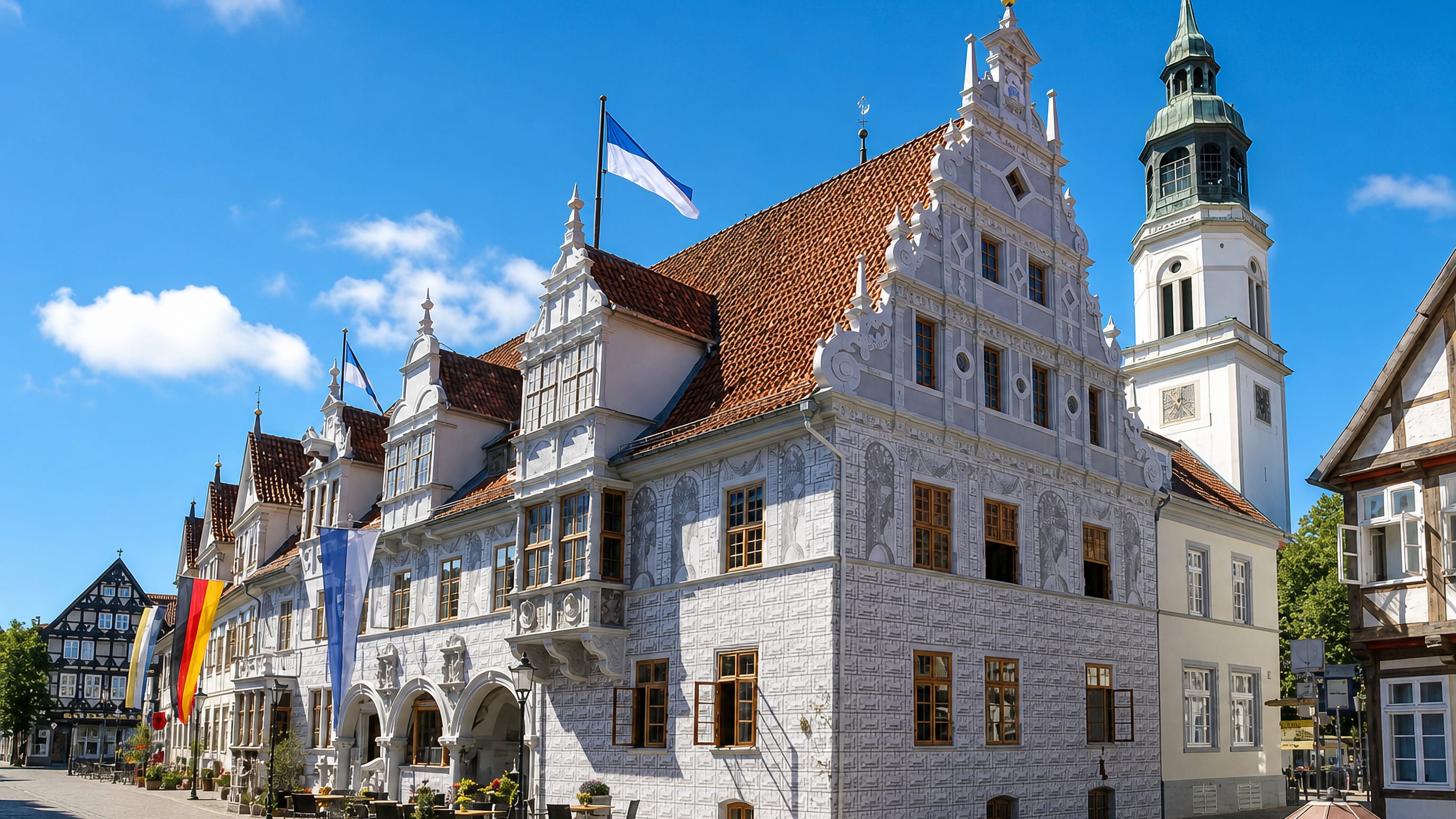 Celle's white Renaissance Old Town Hall and the St Marien church tower above a cobbled old-town street