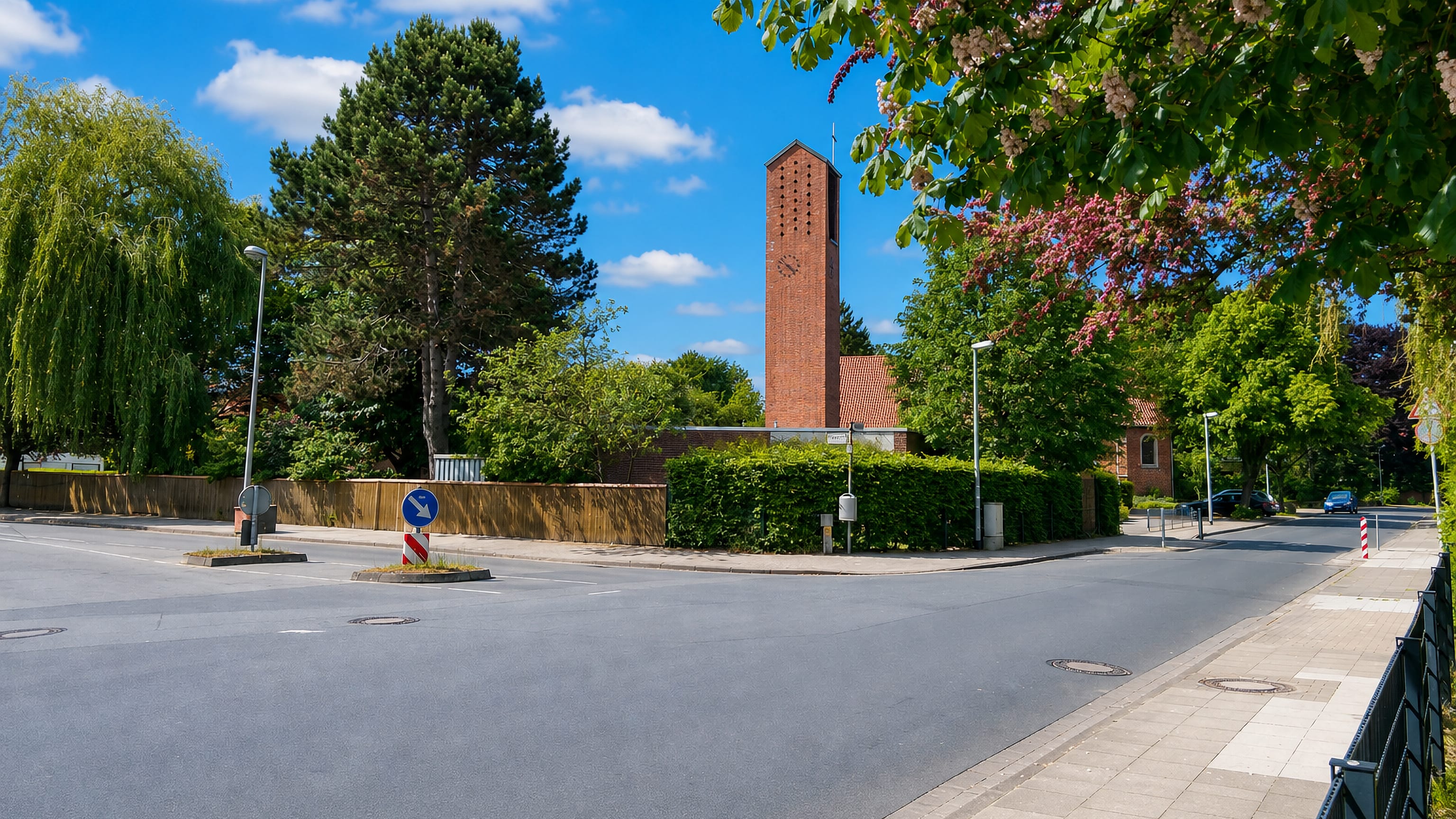 Anderten in Hannover, with a tall brick church tower and clock above a quiet residential street corner.